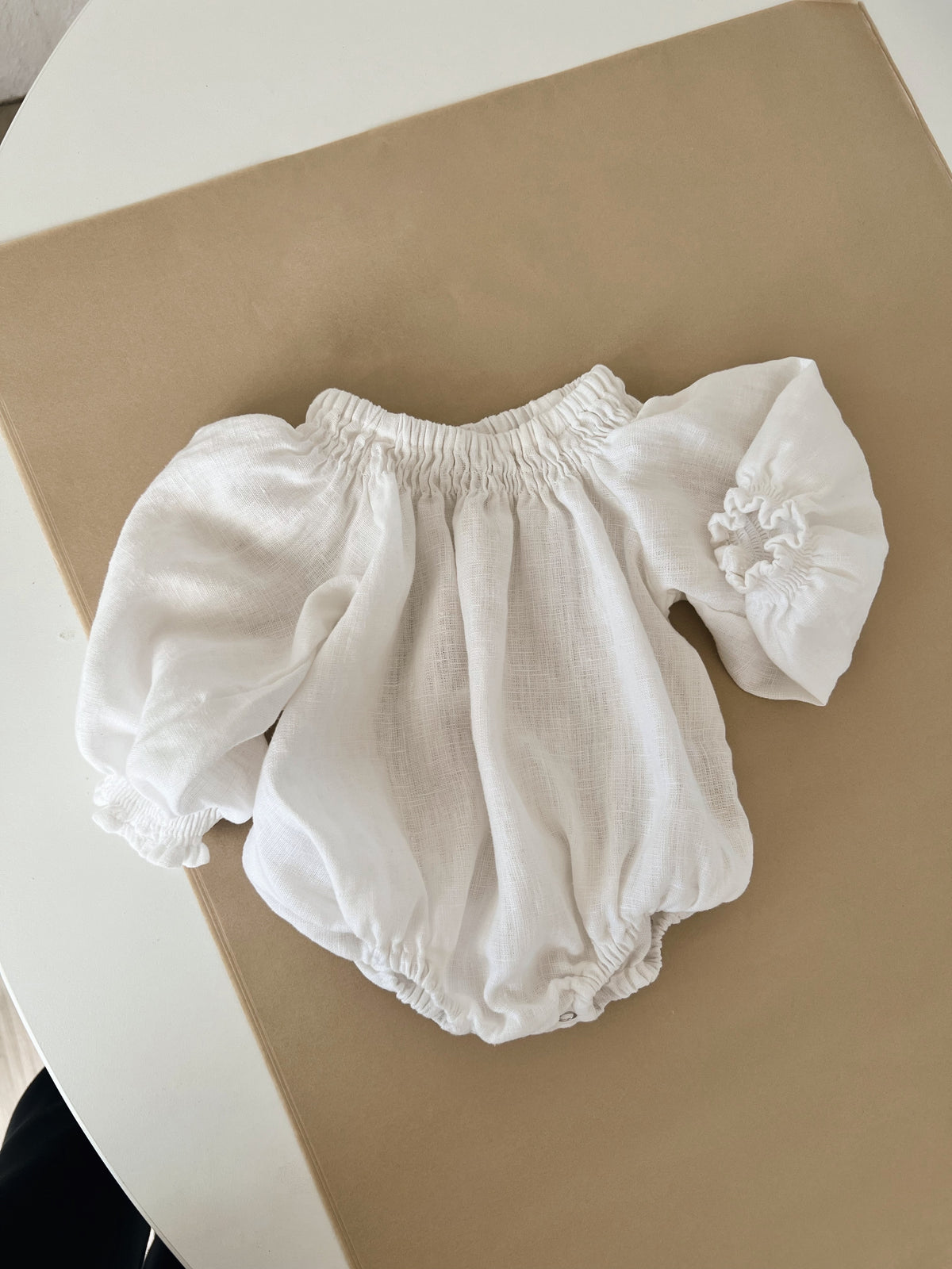 Baby linen white Marlow and Mae Mira romper on wrapping paper